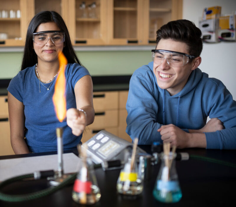 two students working with fire in science class