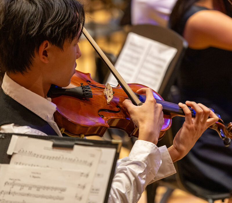 student in orchestra playing the violin