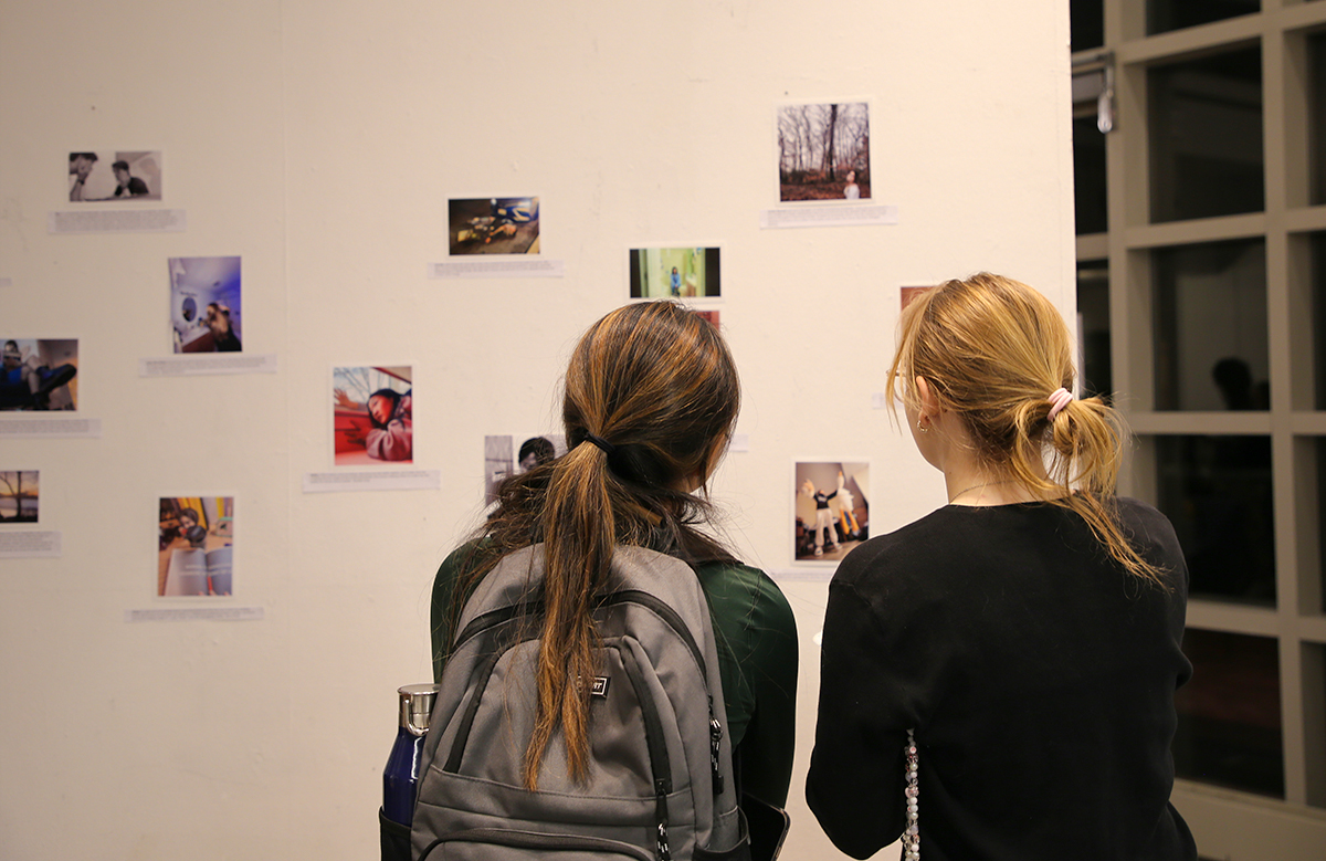 two girls looking at photos on the art gallery wall