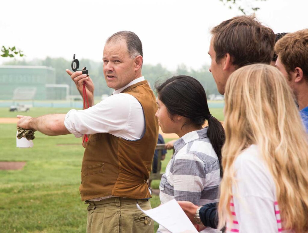 Paul Watkins demonstrates the use of a lensatic compass with a history class.
