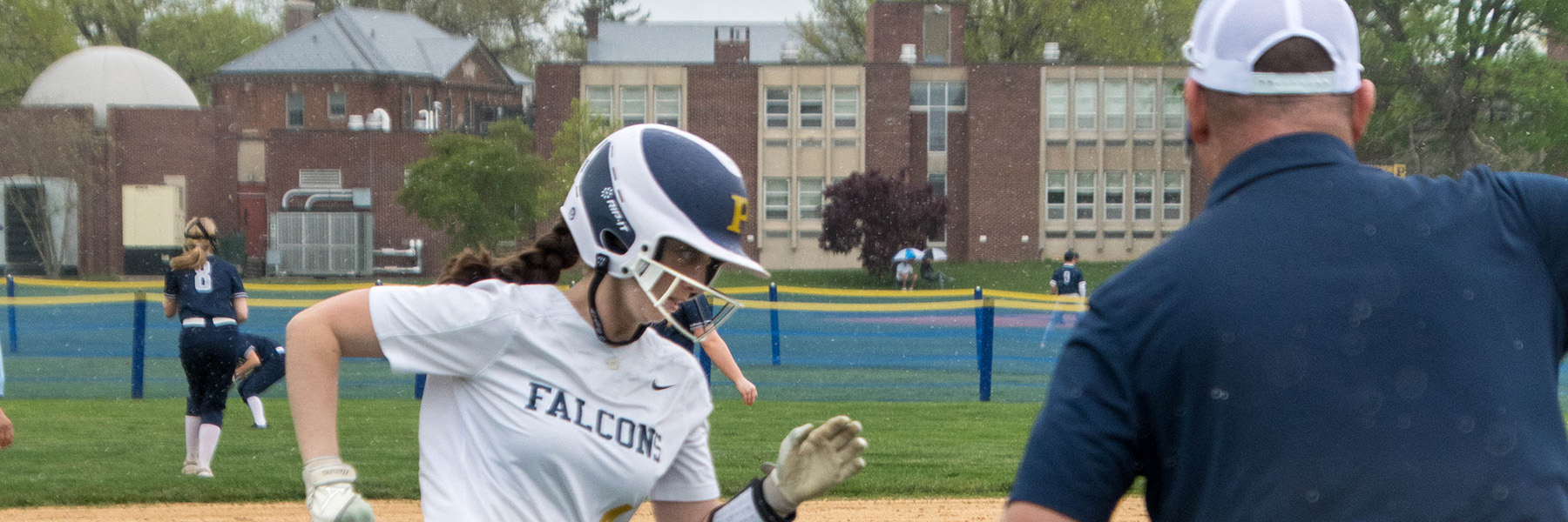 Tom Meneskie coaches a Peddie girls softball player at third base