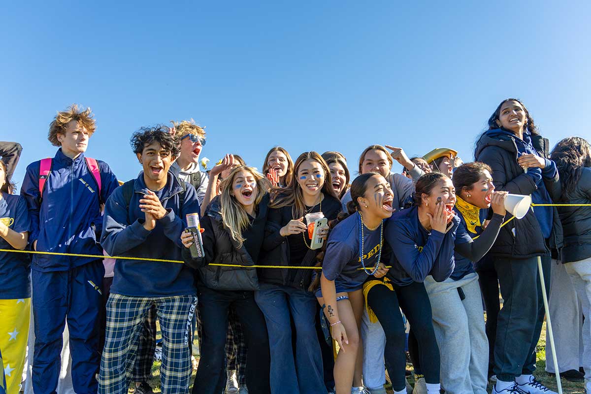 students cheering on the sidelines dressed in blue and gold
