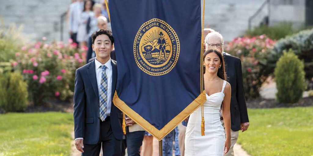 student leaders walking with the Peddie seal banner